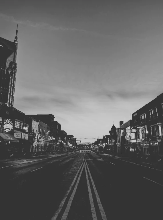 Lower Broadway stands empty at first light in black and white, honky-tonk signs crowding both sidewalks and a spire-topped tower rising at the far left