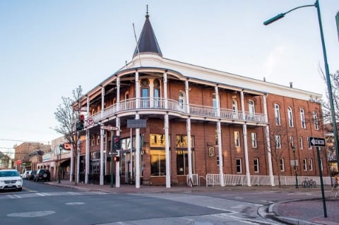 Historic three-story brick corner building with wraparound balcony and turret in Flagstaff