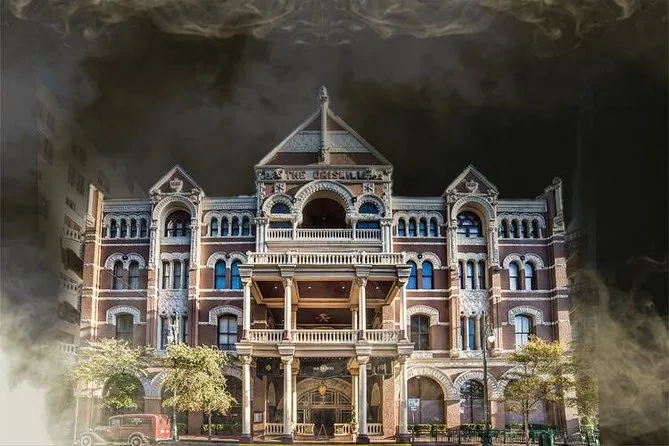 The Driskill's red brick and limestone front, with its arched balconies, corner turrets and central gable, ringed by rolling dark smoke