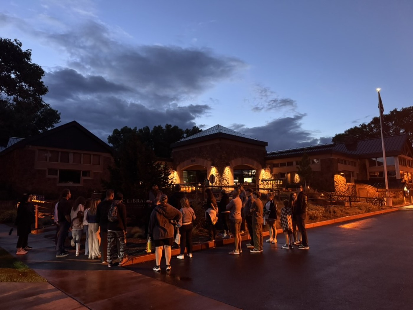 The evening tour lines up outside the lantern-lit library as the last blue light drains from the Flagstaff sky.