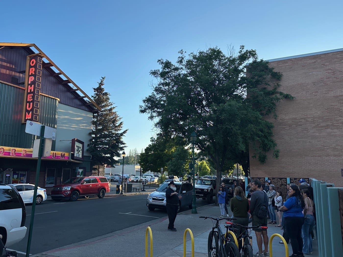 A Freaky Foot Tours guide holds a group's attention on West Aspen Avenue while the Orpheum Theater's neon marquee, glowing over downtown since the early 1900s, burns red behind him.