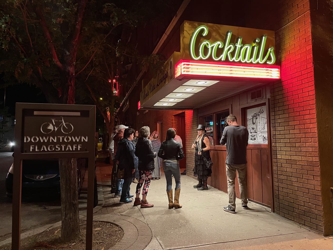 Guests gather beneath the vintage Cocktails marquee of the Monte Vista Lounge, where the haunted pub crawl mixes drinks with stories of the Hotel Monte Vista's phantom bellboy.