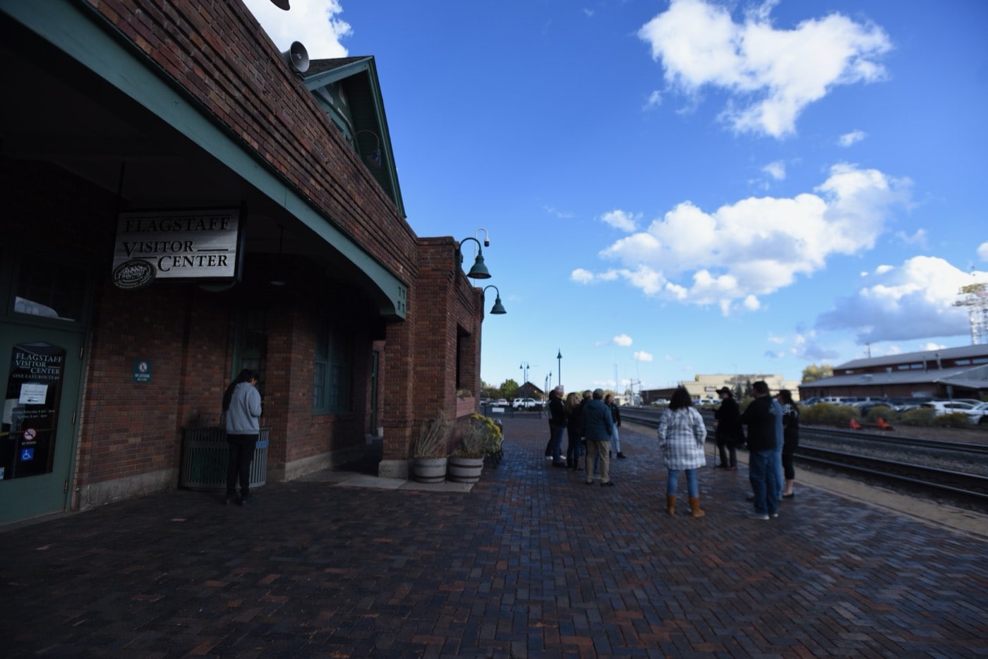 Tour guests gather beneath the Flagstaff Visitor Center sign at the 1926 Tudor Revival train depot, the classic meeting point for a Freaky Foot Tours walk.