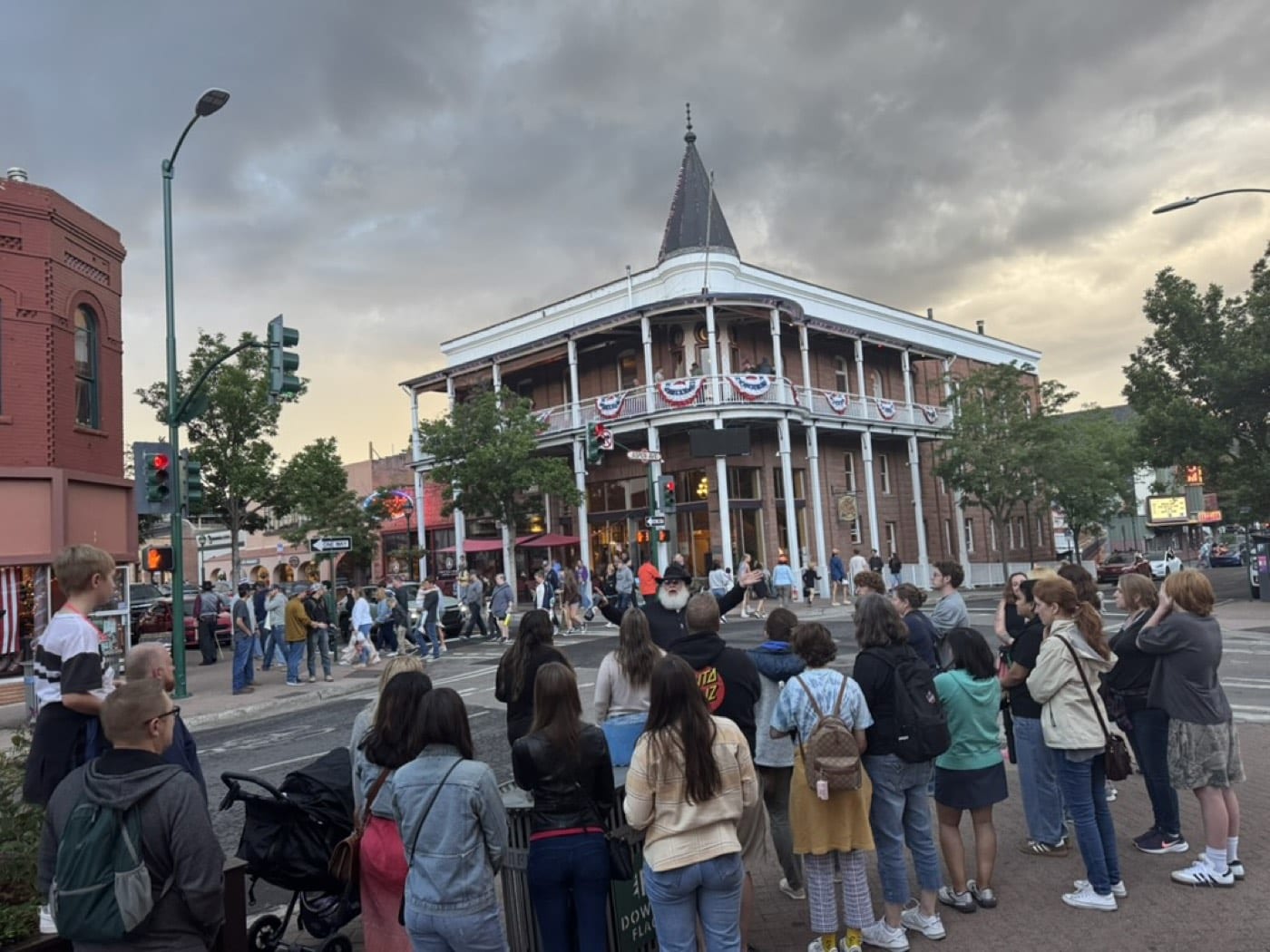 Arms spread wide, the guide claims the corner of Aspen Avenue while banners flutter on the hotel John W. Weatherford opened in 1900.
