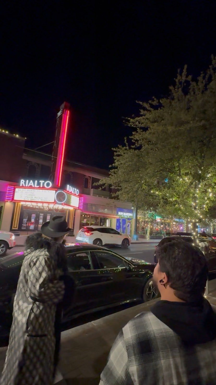A tour group under the Rialto Theatre neon at night