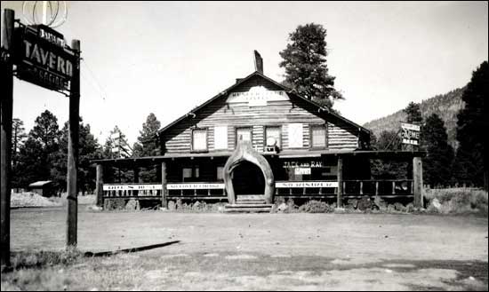Vintage black-and-white log tavern building with a Tavern sign out front