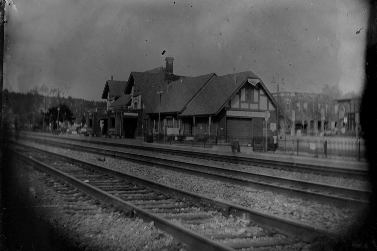 Historic Tudor-style train depot at dusk with railroad tracks in the foreground