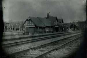 Dark moody view of an old railroad depot beside train tracks at dusk