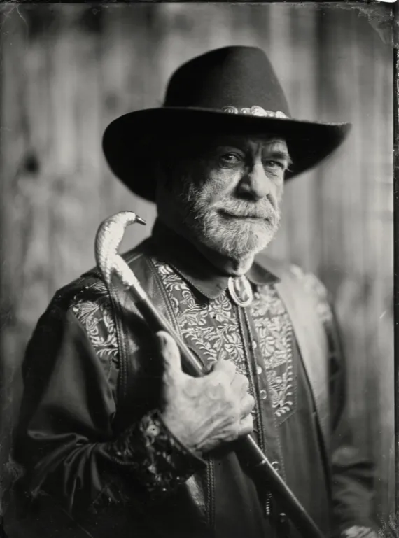 Tintype portrait of a bearded man in a wide brimmed hat with an ornate embroidered jacket