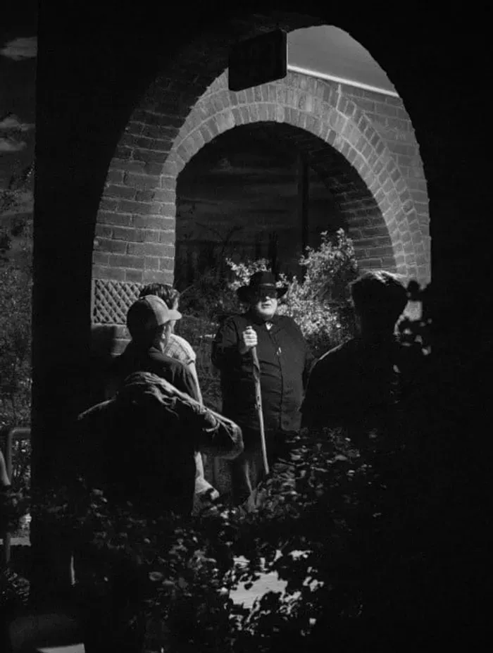 Tour group gathered under a brick archway at night with a guide holding a cane