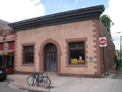 Small red sandstone commercial building with an arched doorway and bikes parked outside