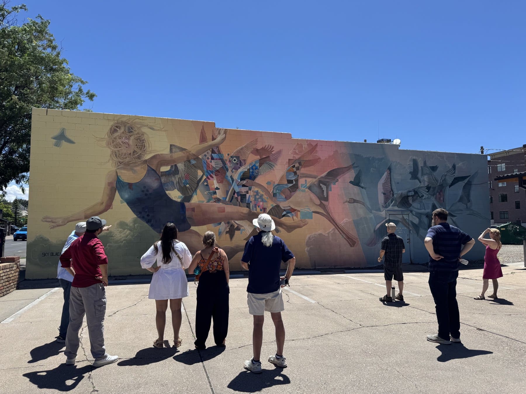 A tour group taking in the full Sound of Flight mural on the Flagstaff mural tour