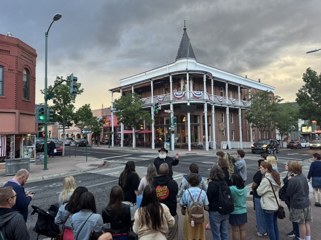 A guide tells stories to a crowd of guests across from the Weatherford Hotel in downtown Flagstaff