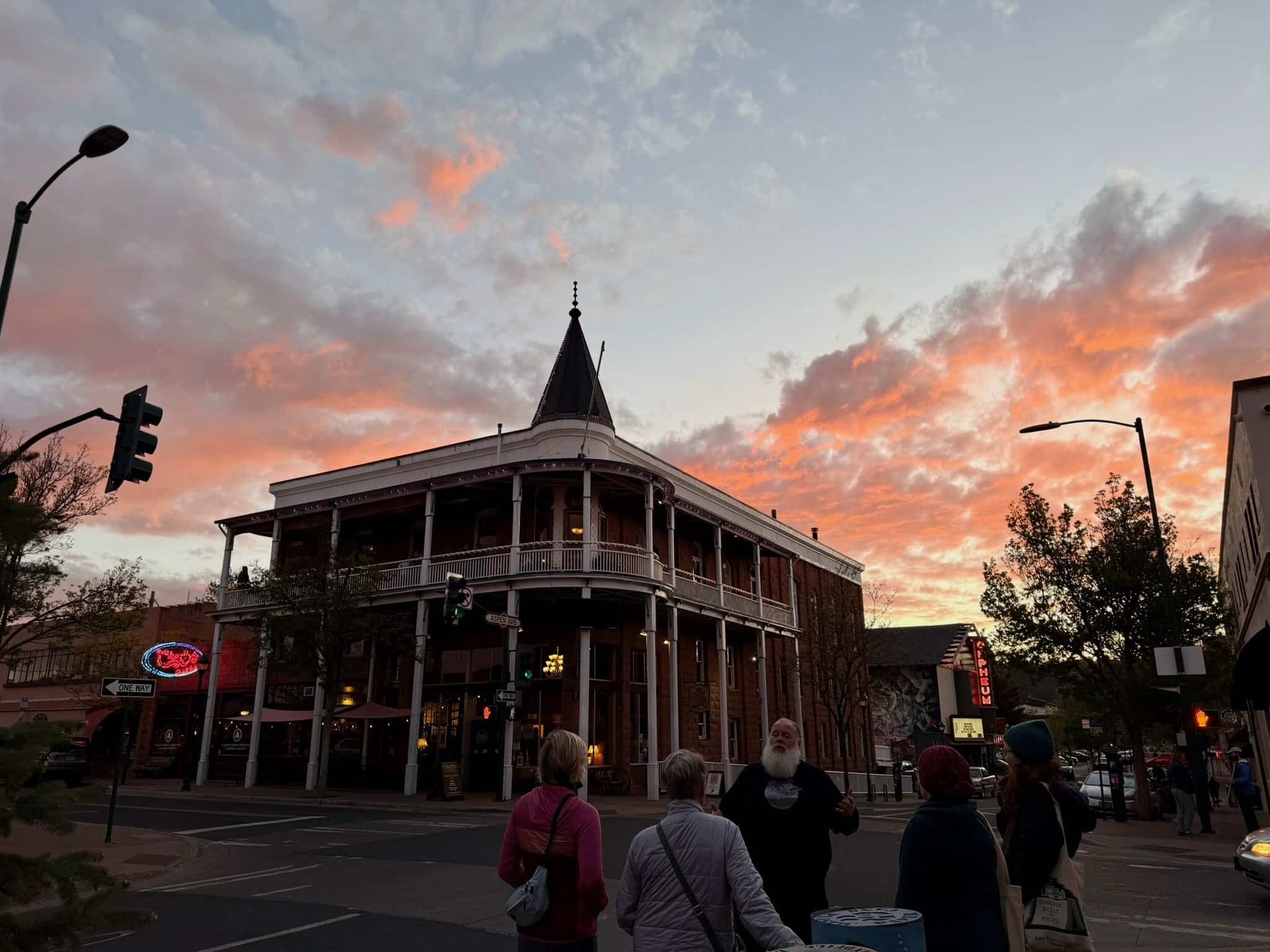 A guide shares a story with guests below the Weatherford Hotel at sunset in downtown Flagstaff