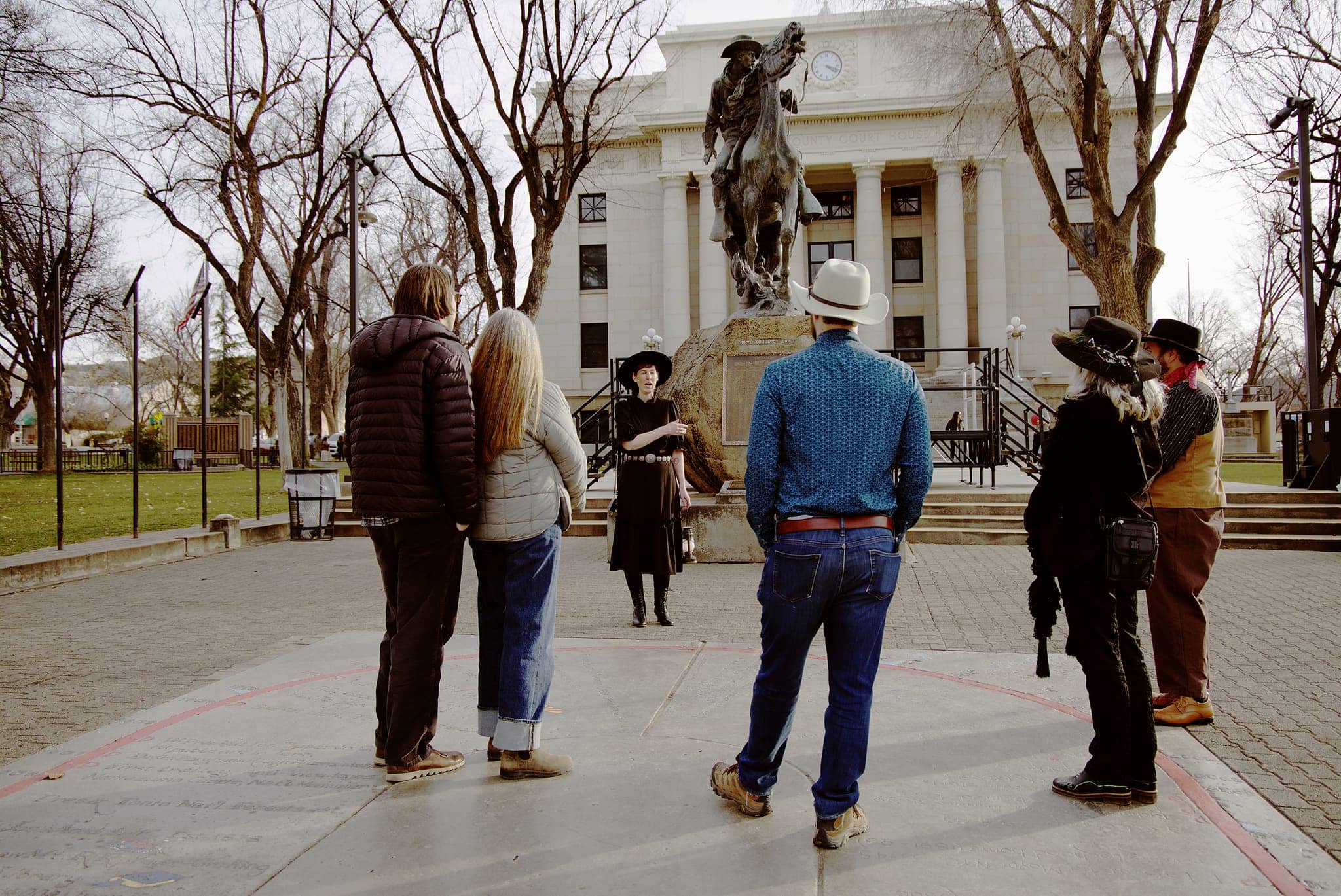 A costumed guide with a lantern tells stories at the Rough Rider statue on Courthouse Plaza in Prescott