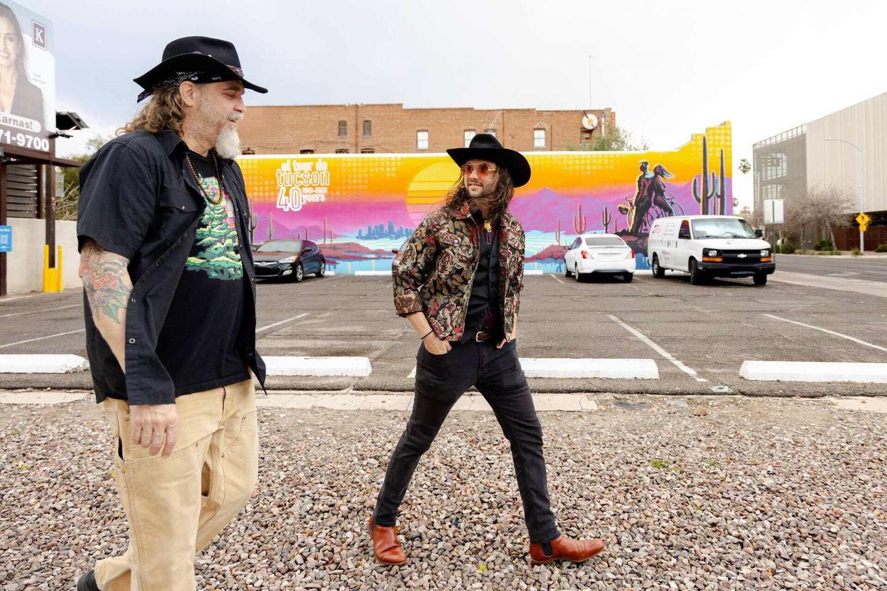 Two Freaky Foot Tours guides walking past Joe Pagac's colorful El Tour de Tucson mural